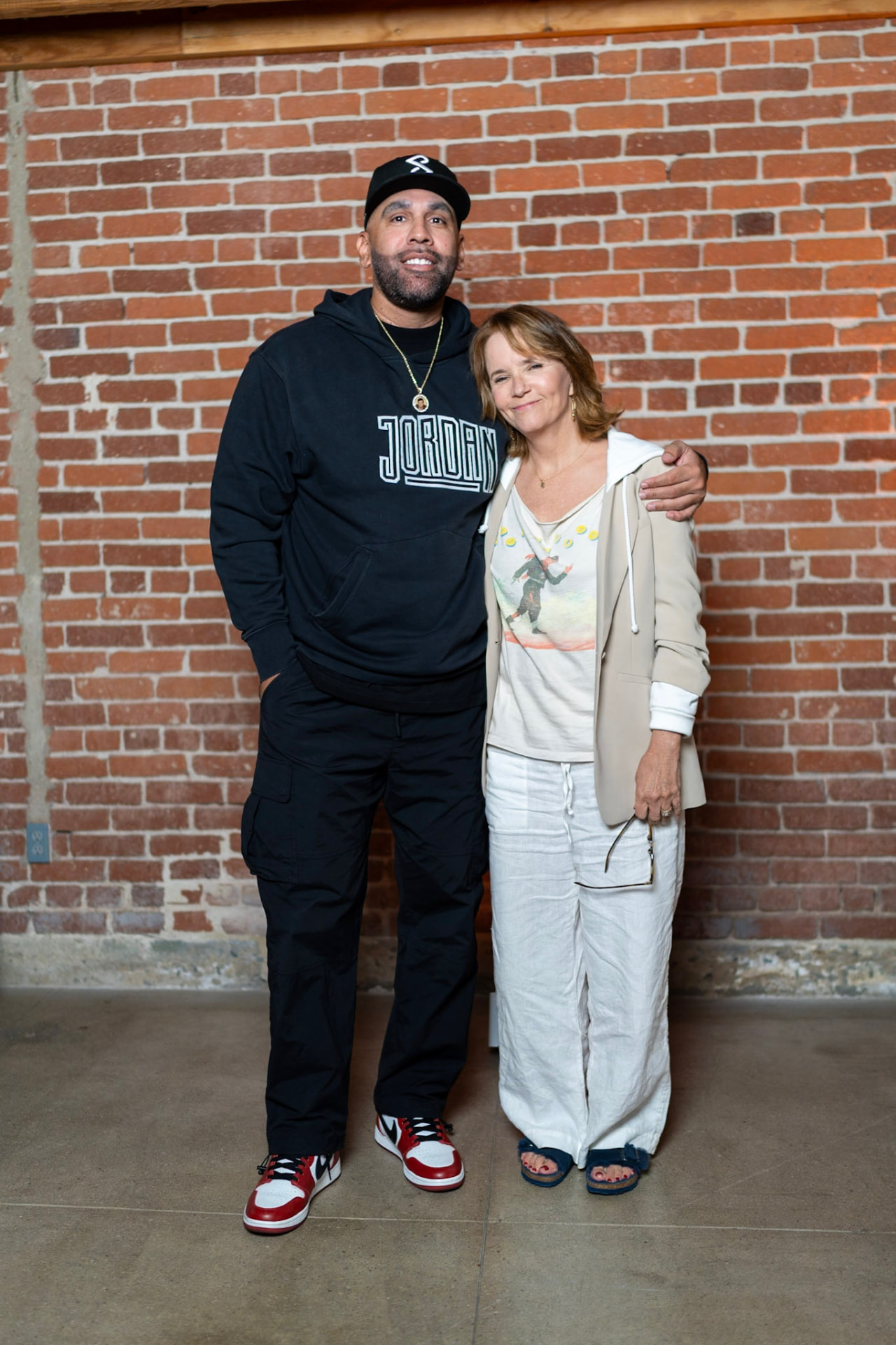 Brian and a guest posing in front of the studio brick wall